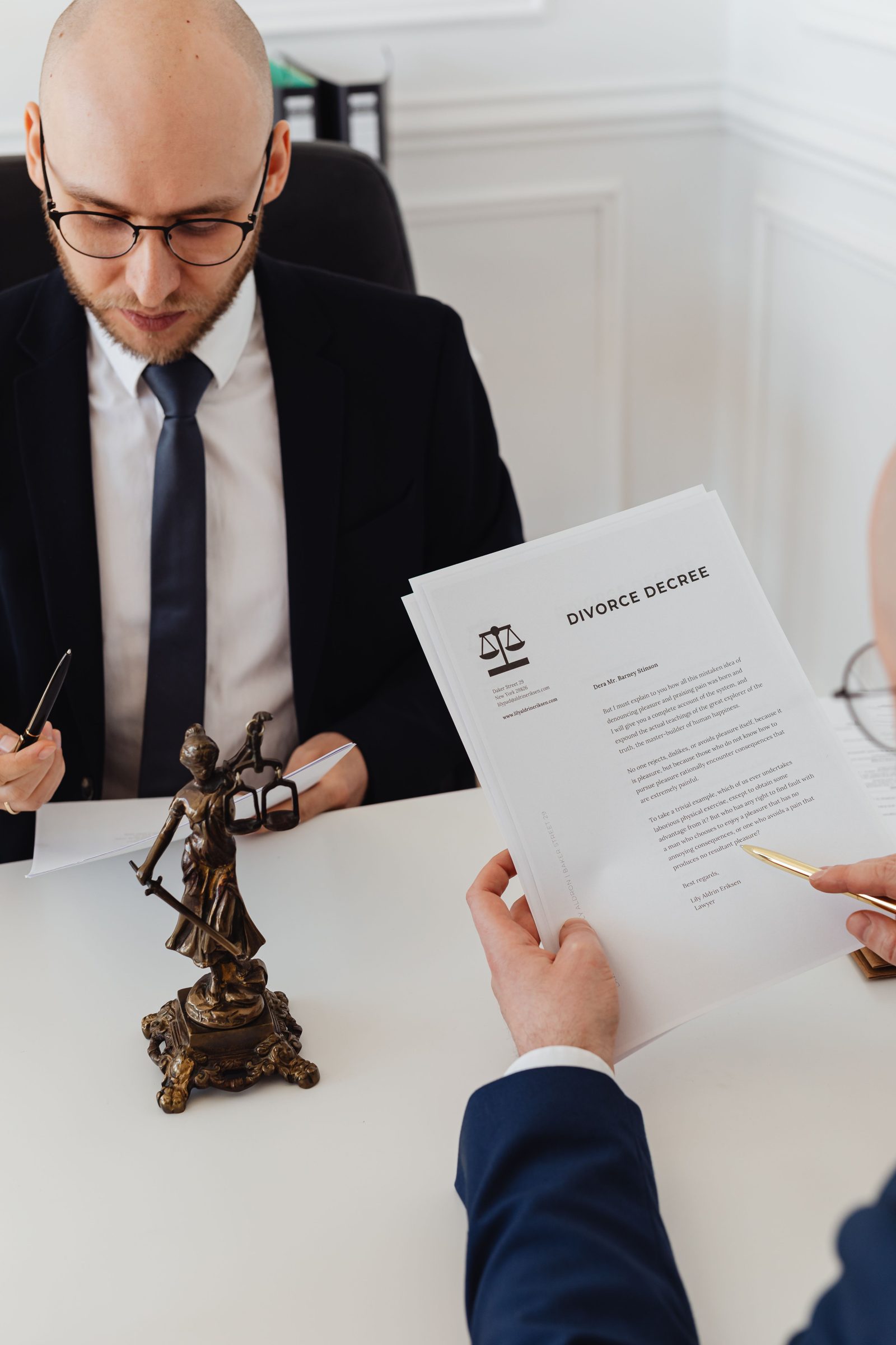 A mediator at a desk with a small statue of justice, holding a divorce decree.