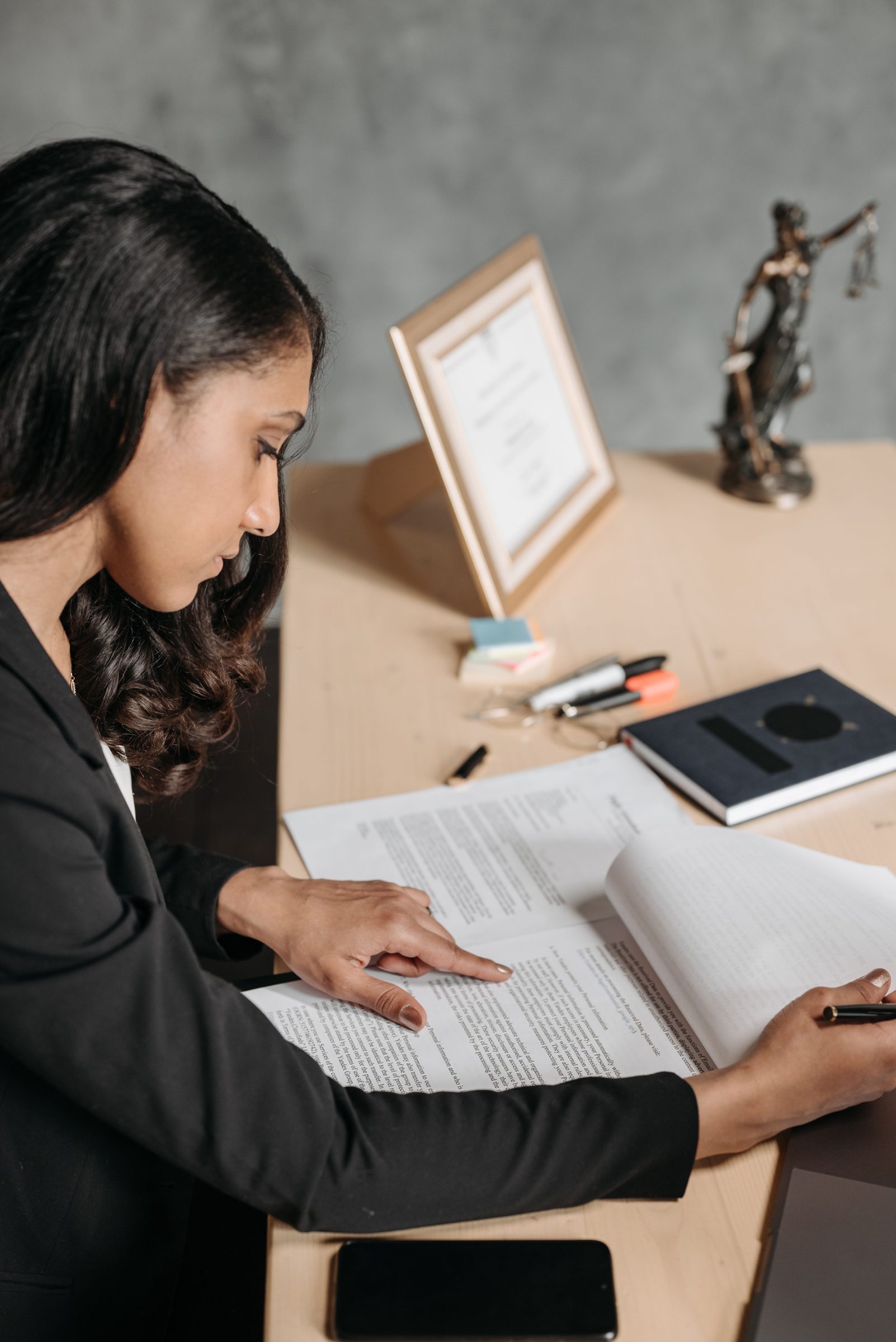A woman reading a document at a desk.