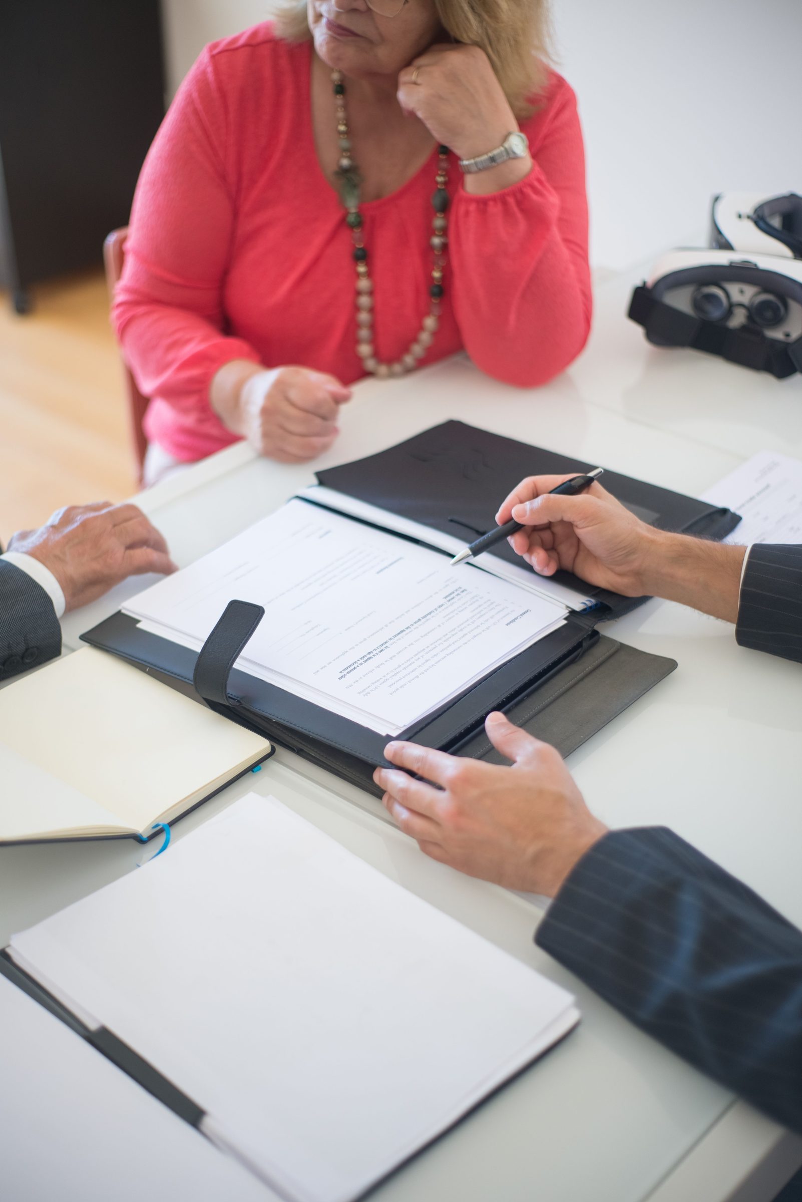 Two people going over papers at a table, one about to sign.