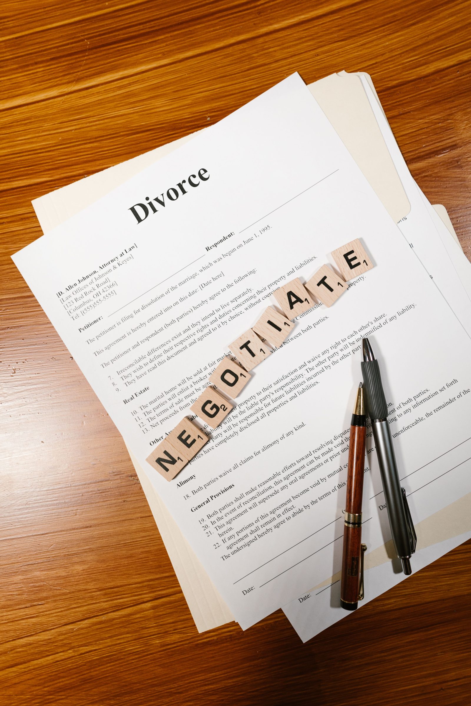Divorce papers on a desk with letter tiles spelling negotiate.